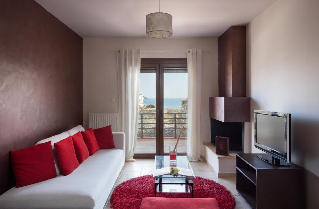 a living room with a white couch and red pillows at Myriam Spa & Luxury Suites in Monemvasia