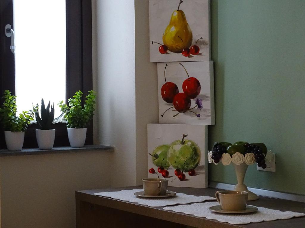 a table with two cups and some plants and paintings at Appartamenti Emilio in Prato