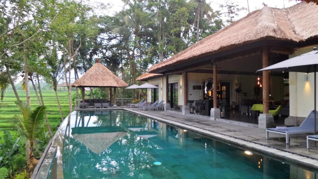 a swimming pool in front of a villa at Rouge - Private Villa Condense in Ubud