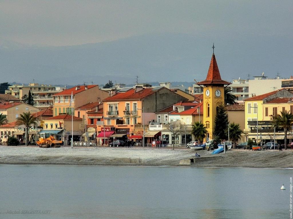 a town with a clock tower next to a body of water at Appartements Au Cros De Cagnes in Cros-de-Cagnes
