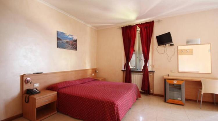 a bedroom with a red bed and a tv at Hotel Villa Flora in Bogliasco