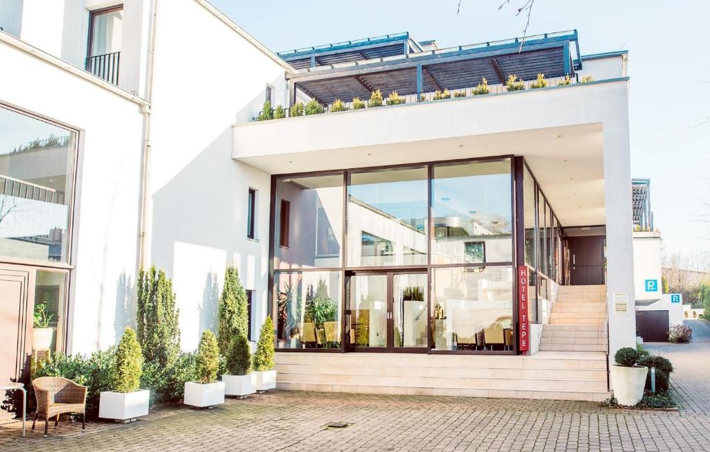 ein weißes Haus mit Glastüren und Topfpflanzen in der Unterkunft Lindenhof Hotel Tepe in Damme