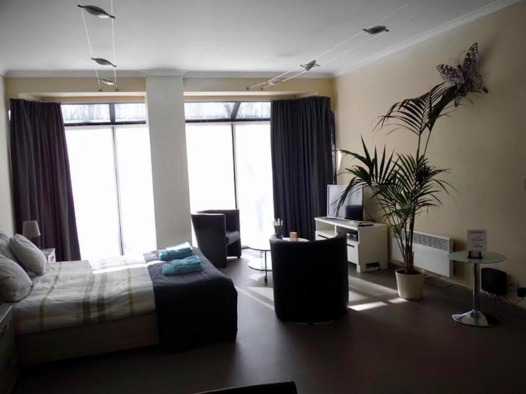 ein Schlafzimmer mit einem Bett und ein Wohnzimmer mit Fenstern in der Unterkunft Residentie Royal Park in Ostende