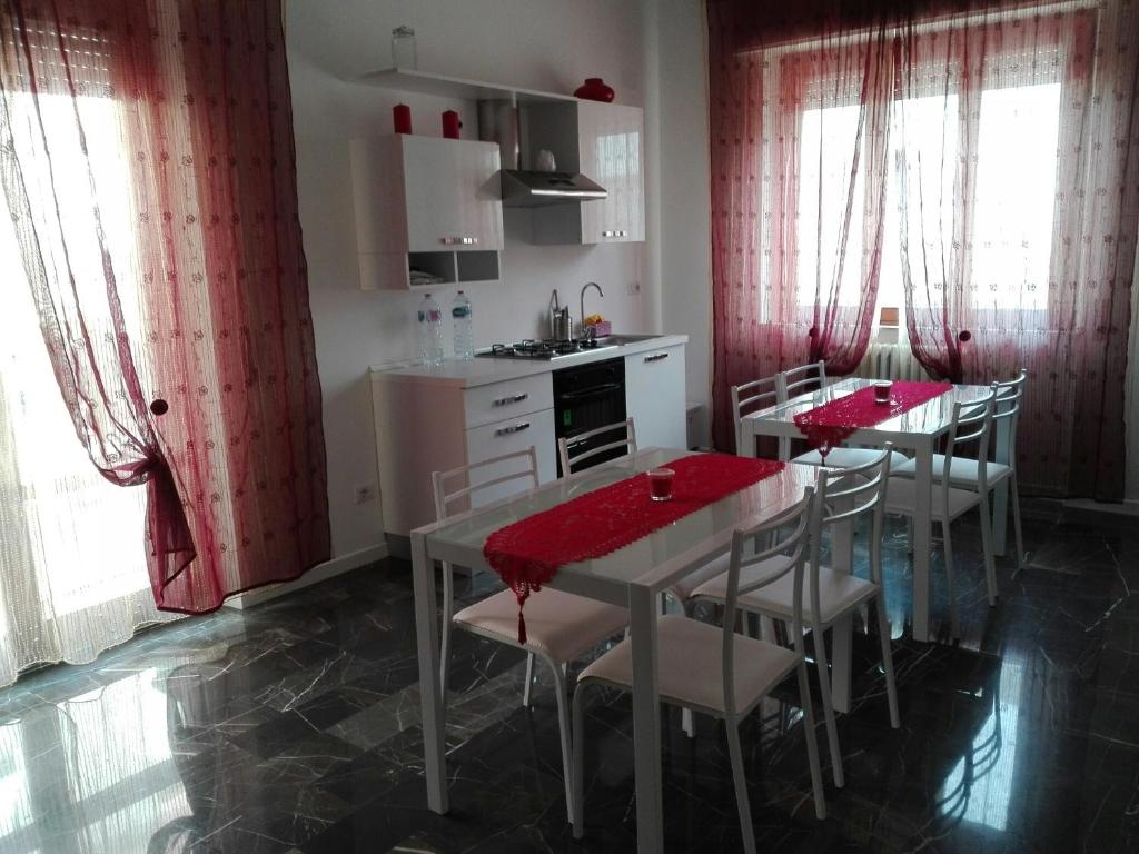 una cucina con tende rosse, tavolo e sedie di Casa Dilva a Porto SantʼElpidio