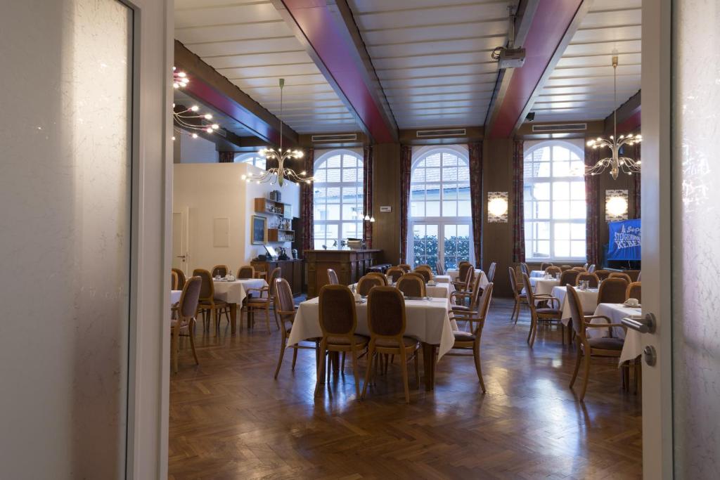 a dining room with tables and chairs and windows at Hotel Gasthof Zum Storch in Schlüsselfeld