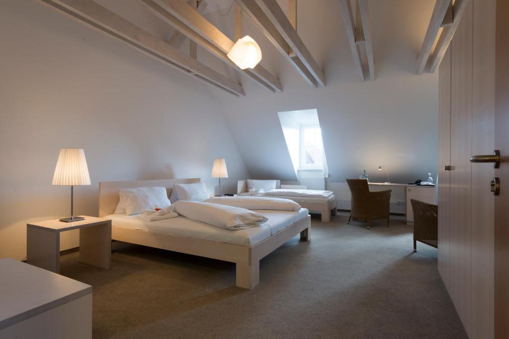 a white bedroom with two beds and a table and a desk at Hotel Gasthof Zum Storch in Schlüsselfeld