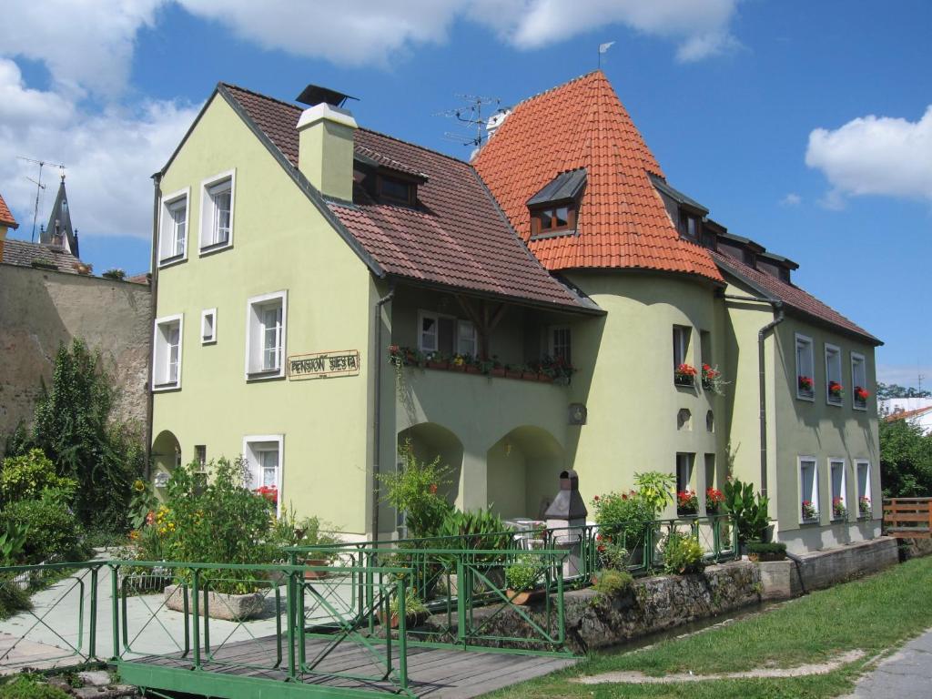 une grande maison jaune avec un toit rouge dans l'établissement Pension Siesta, à Třeboň