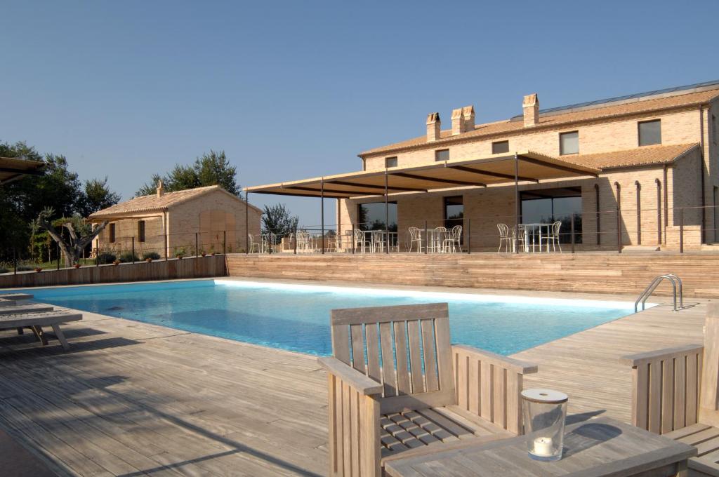 una piscina con 2 bancos y una casa en Solea Relais di Charme- Adults only, en Trecastelli