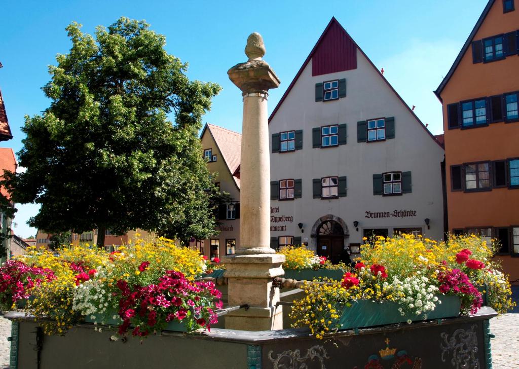 una fuente con flores frente a un edificio en Hotel Haus Appelberg en Dinkelsbühl