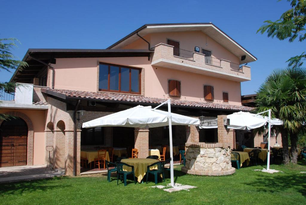 a house with tables and umbrellas in front of it at Country House Il Piacere in Civitella del Tronto
