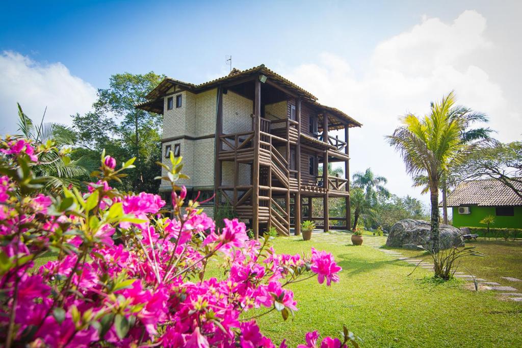 a house with pink flowers in front of it at Cabanas do Araça Villa in Porto Belo