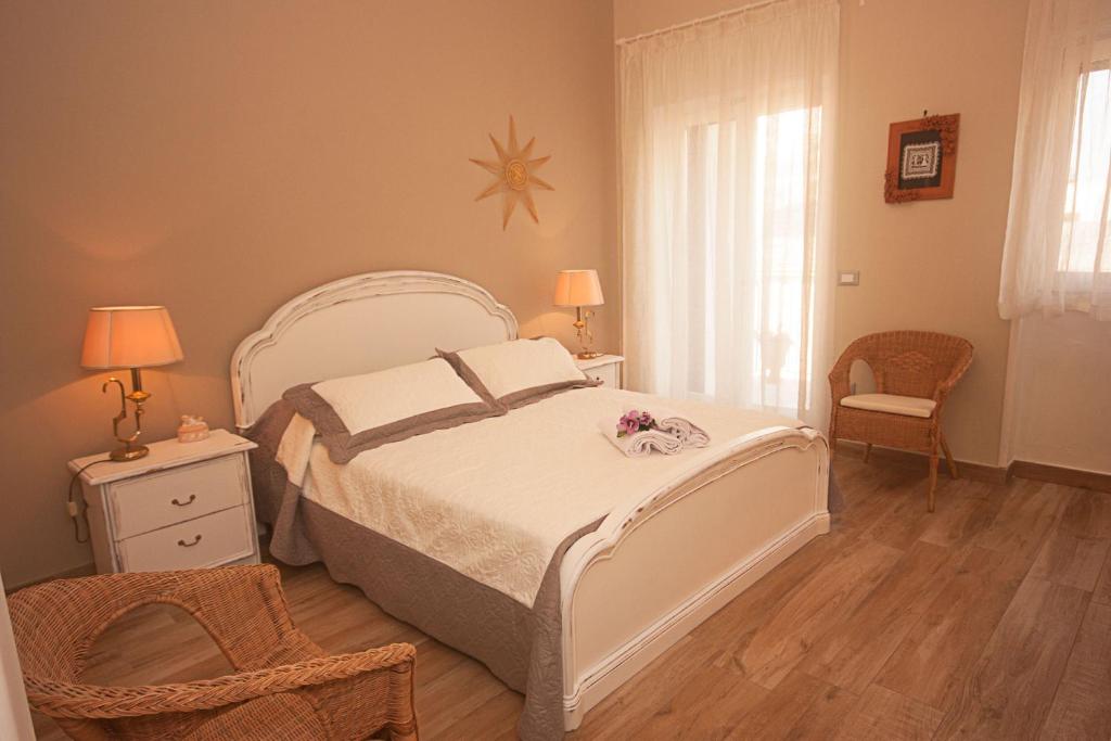 ein Schlafzimmer mit einem weißen Bett und einem Stuhl in der Unterkunft Il Punto a Maglie in Maglie