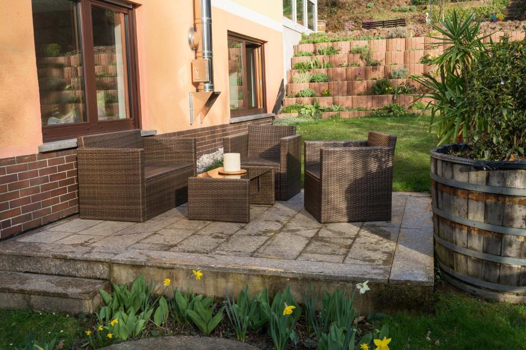 a patio with wicker chairs and a table and a barrel at Zum Ehranger Wald 2a in Trier