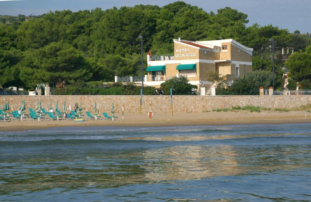 a beach with chairs and a building in the background at Hotel Vela Velo Club Vieste in Vieste