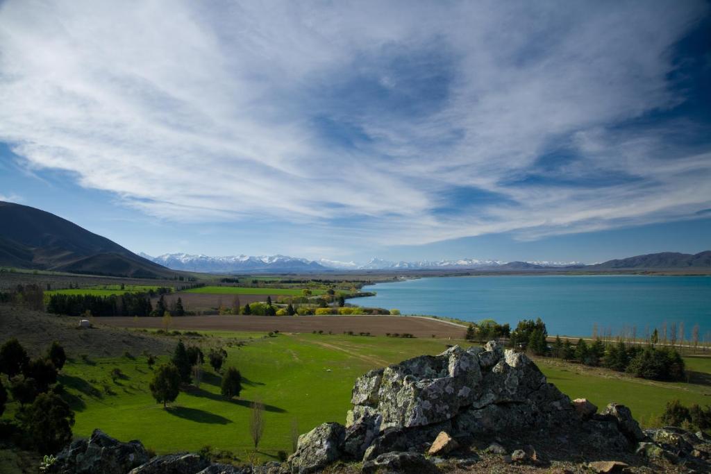 a view of a field and a lake with mountains at Quail Rest in Twizel