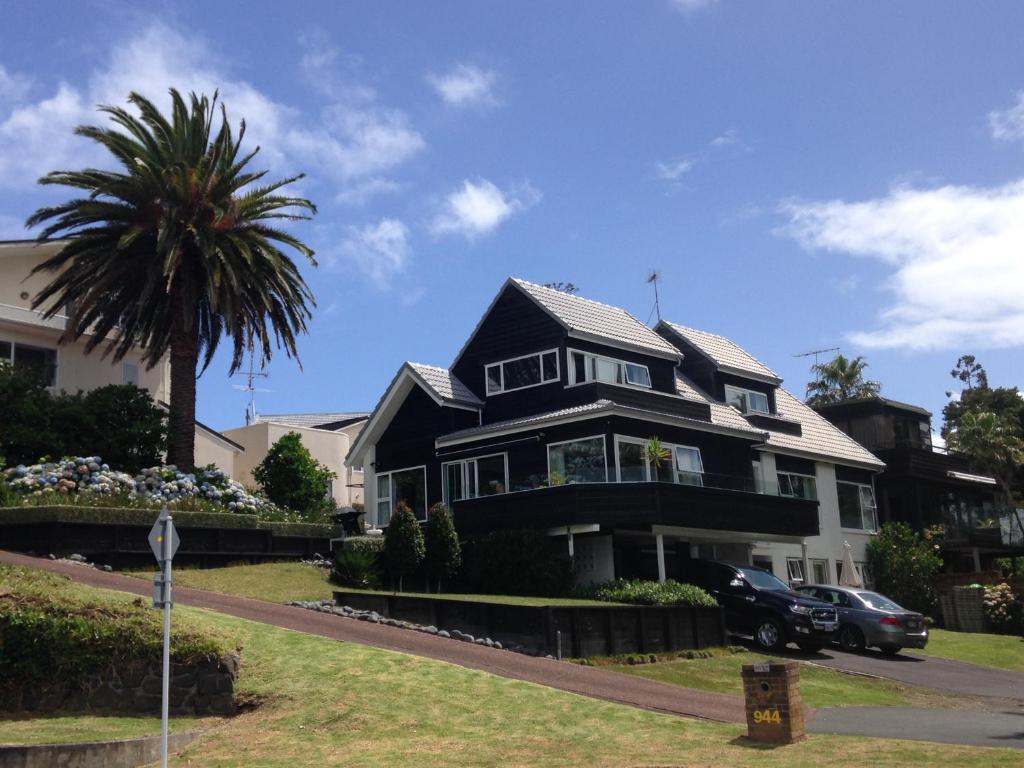 a black house with a palm tree in front of it at Beach Side B & B in Auckland