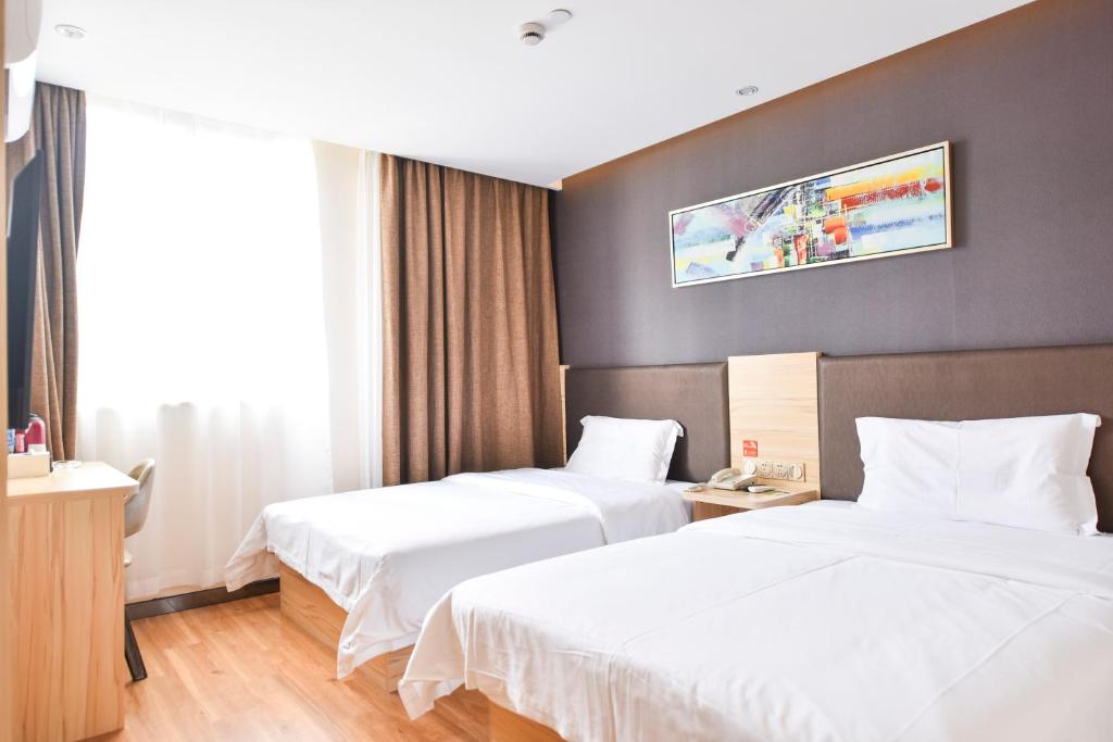 Cette chambre comprend 2 lits et une télévision murale. dans l'établissement 7Days Premium Shanghai Wild Animal Park, à Nanhui
