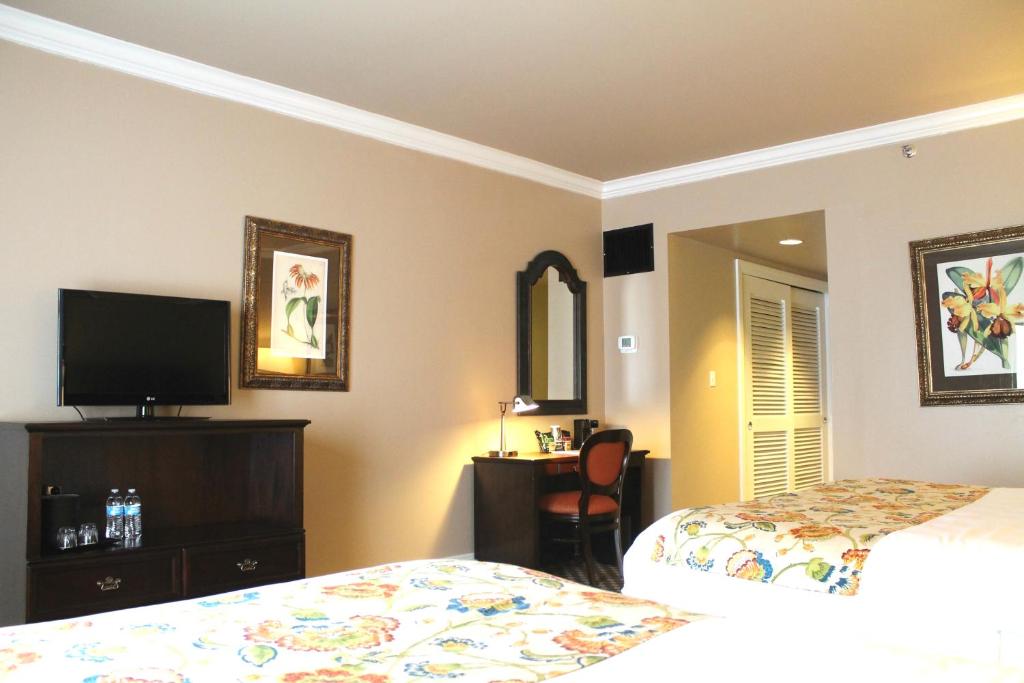 a bedroom with two beds and a desk and a tv at Menger Hotel in San Antonio