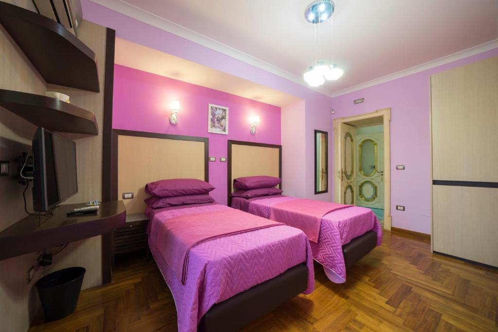 a pink room with two beds and a tv at B&B 'O Sole Mio! in Naples