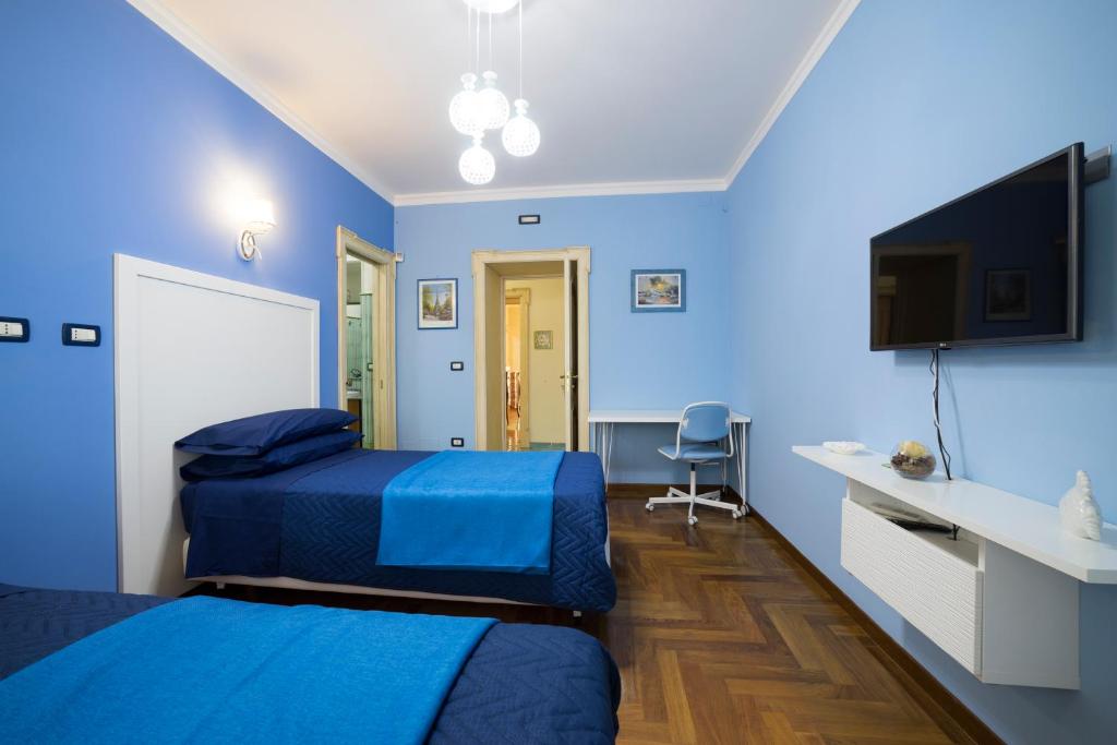 a blue room with two beds and a flat screen tv at B&B 'O Sole Mio! in Naples