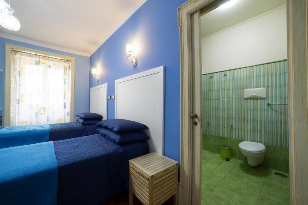 a blue bedroom with two beds and a toilet at B&B 'O Sole Mio! in Naples