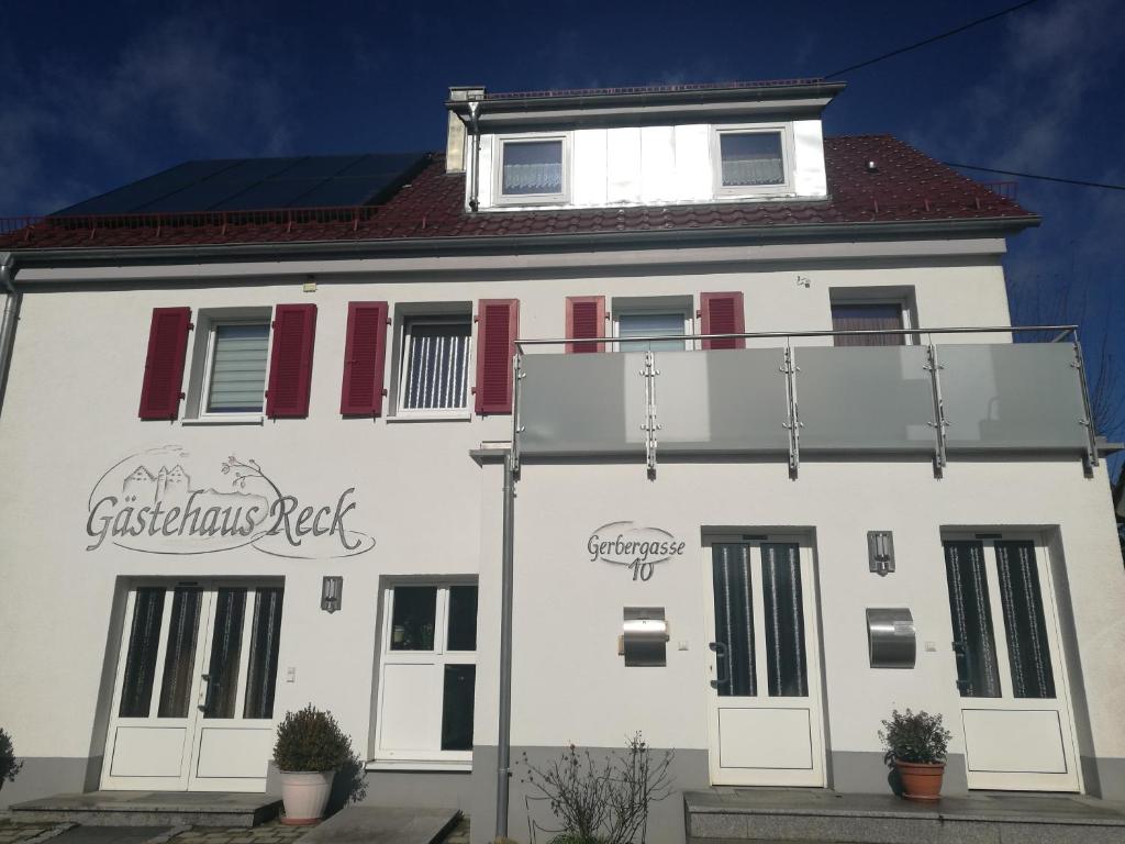 un edificio blanco con persianas rojas. en Pension und Restaurant Reck, en Aulendorf