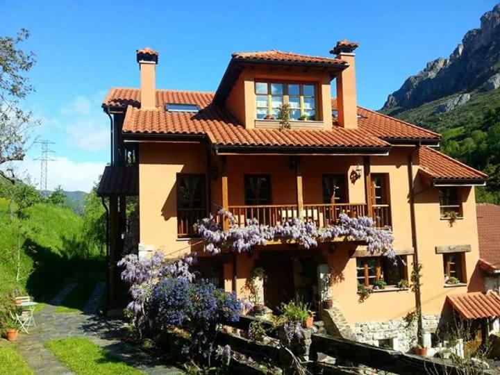 een groot huis met een balkon en paarse bloemen bij Apartamentos Rurales Buenamadre in Pola de Somiedo