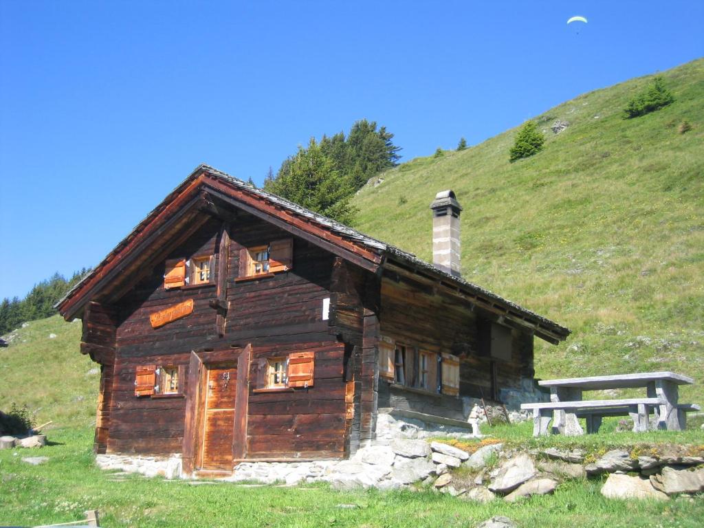 a log cabin on a hill with a bench in front at Alphütte Bielerchäller in Fiesch