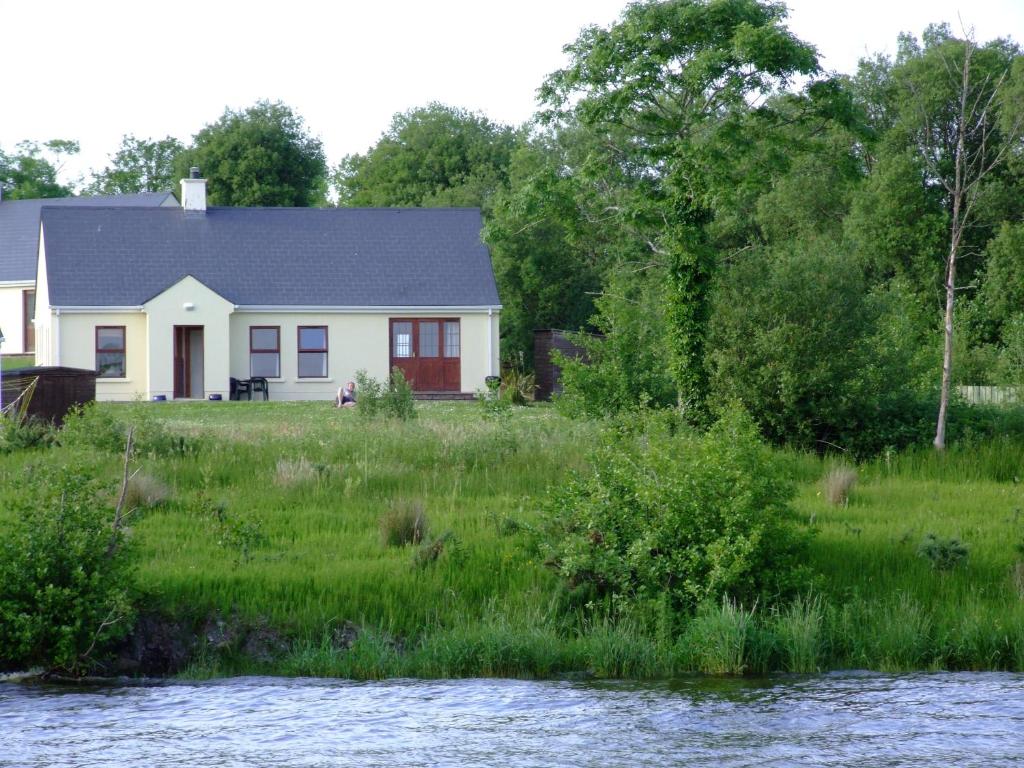 a white house with a red door next to a river at Kesh Lakeside Cottage in Kesh