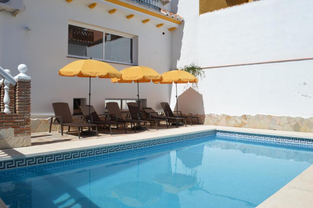 una piscina con sillas y sombrillas junto a un edificio en B&B Casa AriGiLi, en Fuengirola