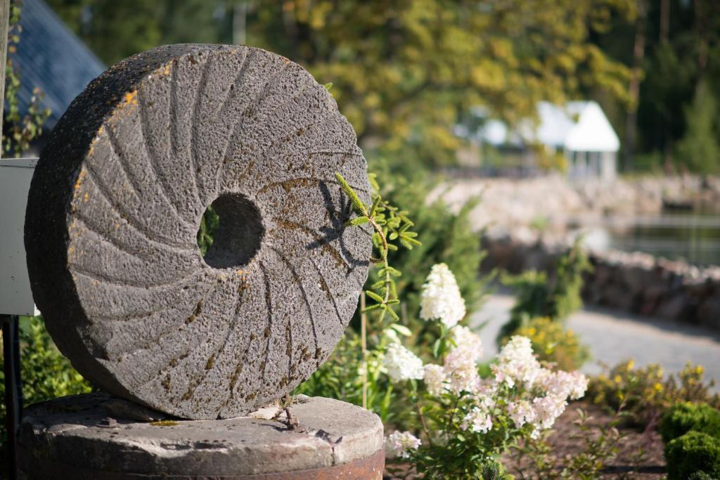 eine Felsstatue in einem Garten mit Blumen in der Unterkunft Dzirnavkalns in Cesvaine