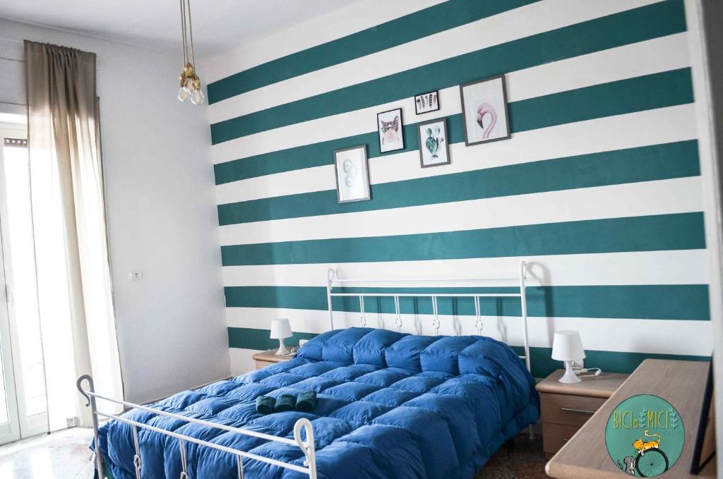 Sofá azul en una habitación con pared a rayas en BICIaMICI Apartments, en Scafati