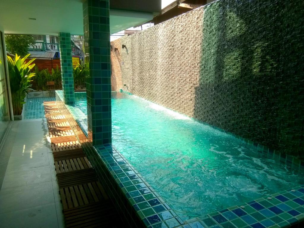 a swimming pool with blue tiles on a building at Hotel De Nara in Chiang Mai