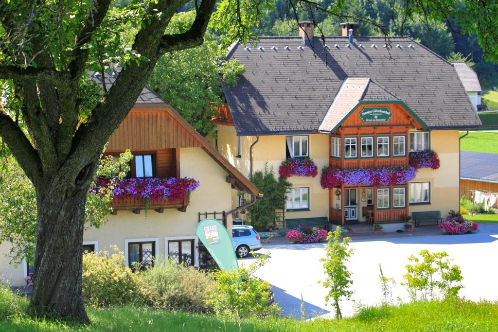 ein großes Haus mit Blumen davor in der Unterkunft Pension Glitschnerhof in Aigen im Ennstal