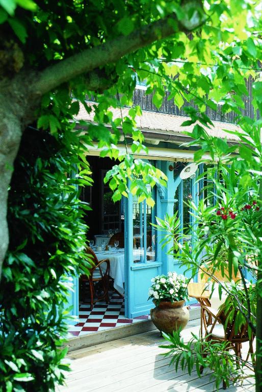 - une terrasse couverte bleue à l'avant d'une maison avec une table et des chaises dans l'établissement La Maison du Bassin, à Cap-Ferret