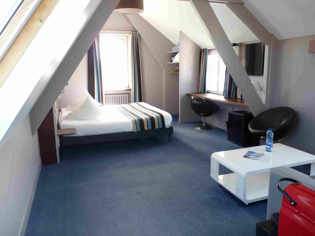 a attic room with a bed and a table at Hôtel des Rochers in Perros-Guirec