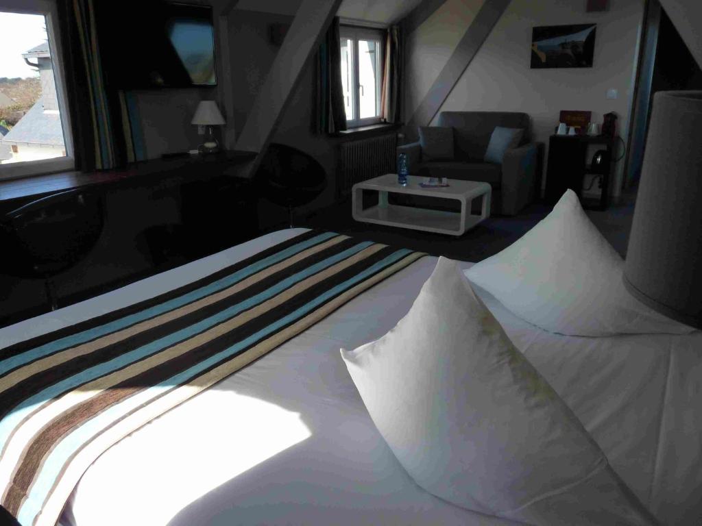 a bedroom with a bed with white sheets and a couch at Hôtel des Rochers in Perros-Guirec