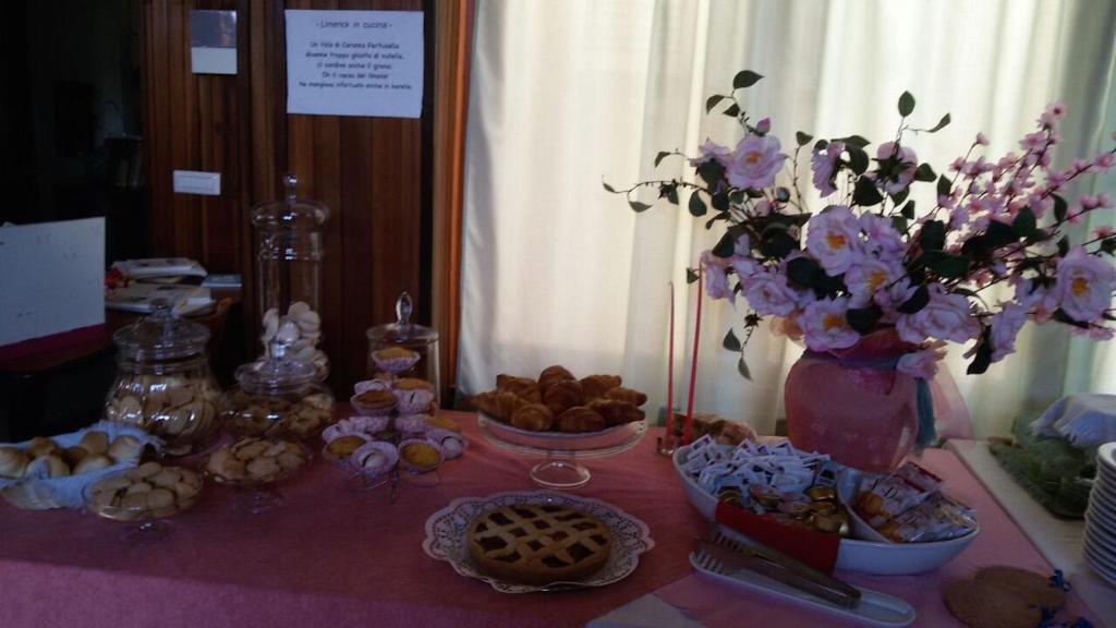 a table with a pink table cloth with food and flowers at Hotel Signorini in Castiglioncello