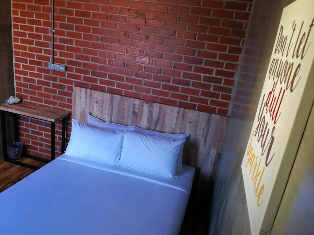 Cama en habitación con pared de ladrillo en The Rise Room en Kuala Terengganu