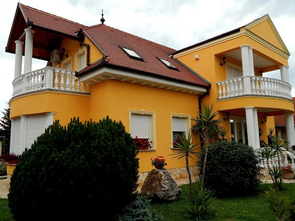 Casa amarilla con ventanas blancas y balcones en Georgina Apartman, en Harkány