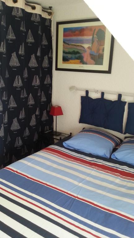 a bedroom with a bed with a blue and red striped blanket at La Maison Du Pecheur in La Trinité-sur-Mer