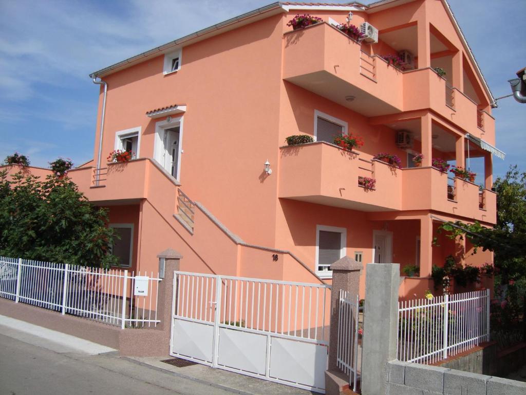 a pink building with balconies and a fence at Niko Apartment in Zadar