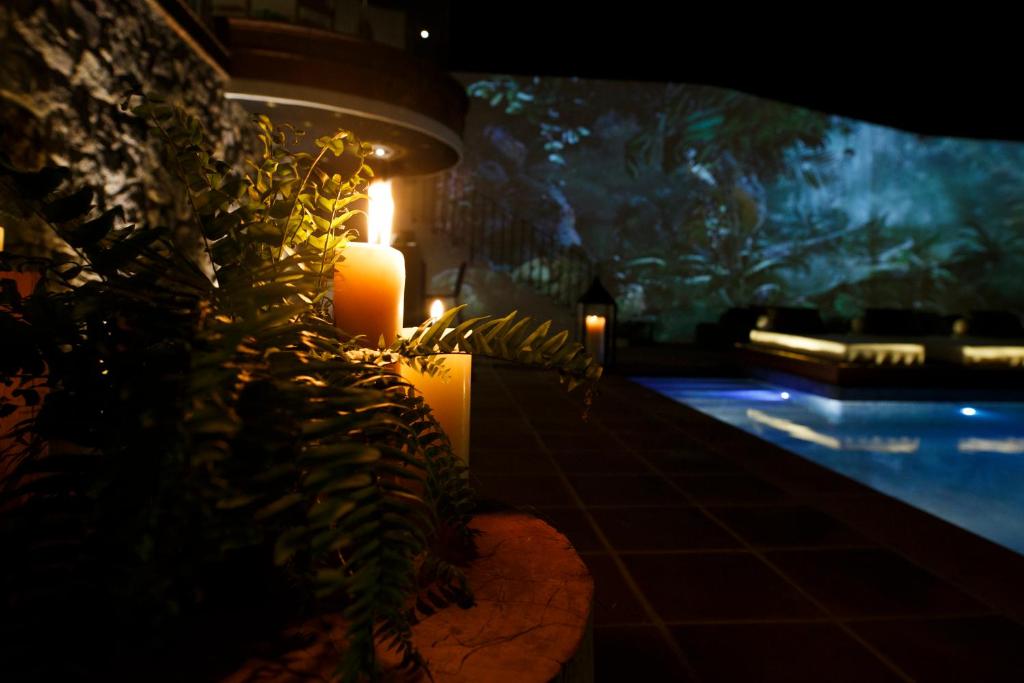 a lit candle next to a swimming pool at night at Maja Hotel Boutique in Morelia