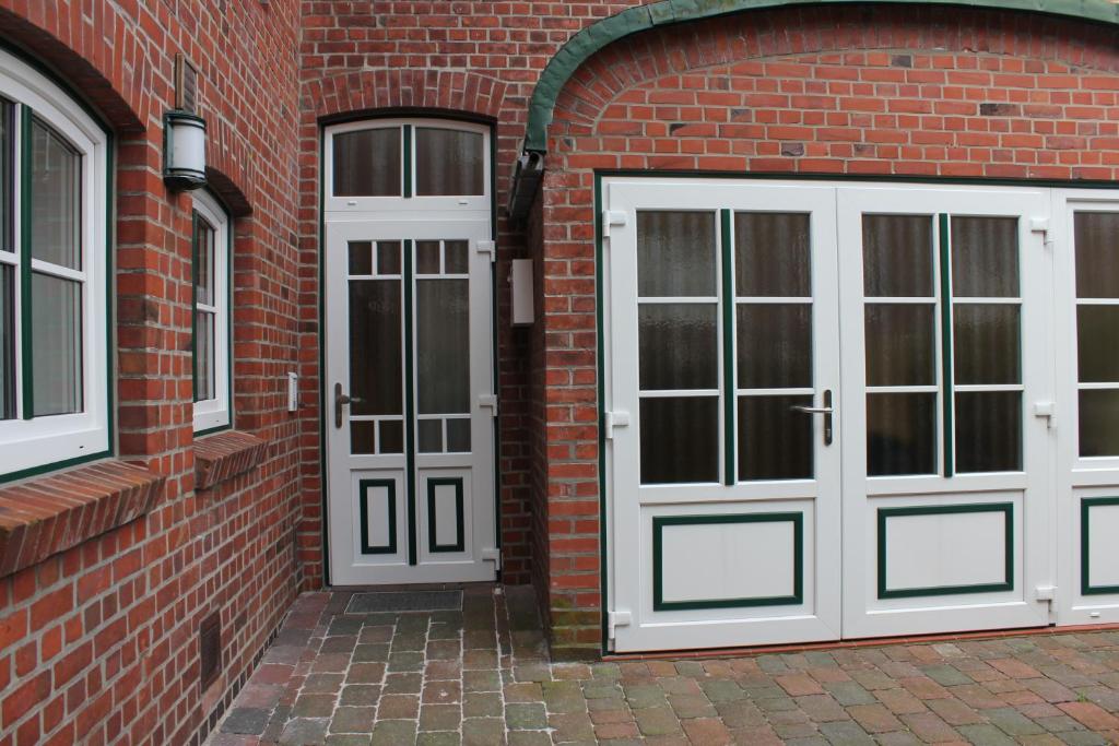 zwei weiße Türen auf einem Backsteingebäude in der Unterkunft Apartment Nuske in Otterndorf
