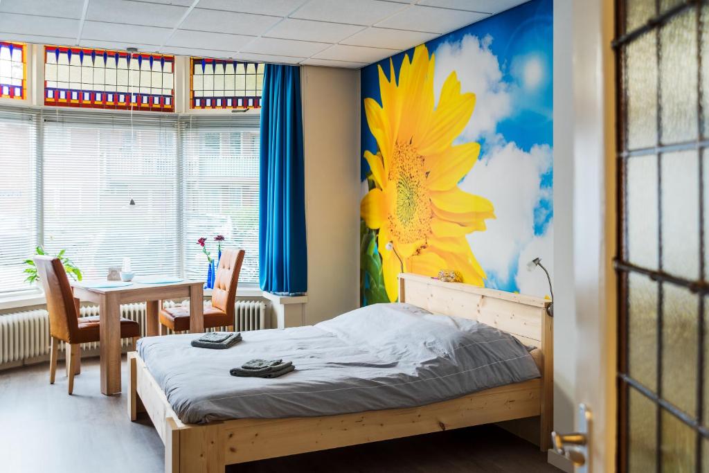 a bedroom with a bed and a table with a flower mural at Studio RoSa in Nijmegen