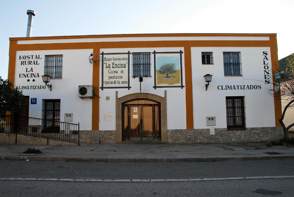 un edificio bianco e arancione con una porta di Hostal la Encina a El Real de la Jara