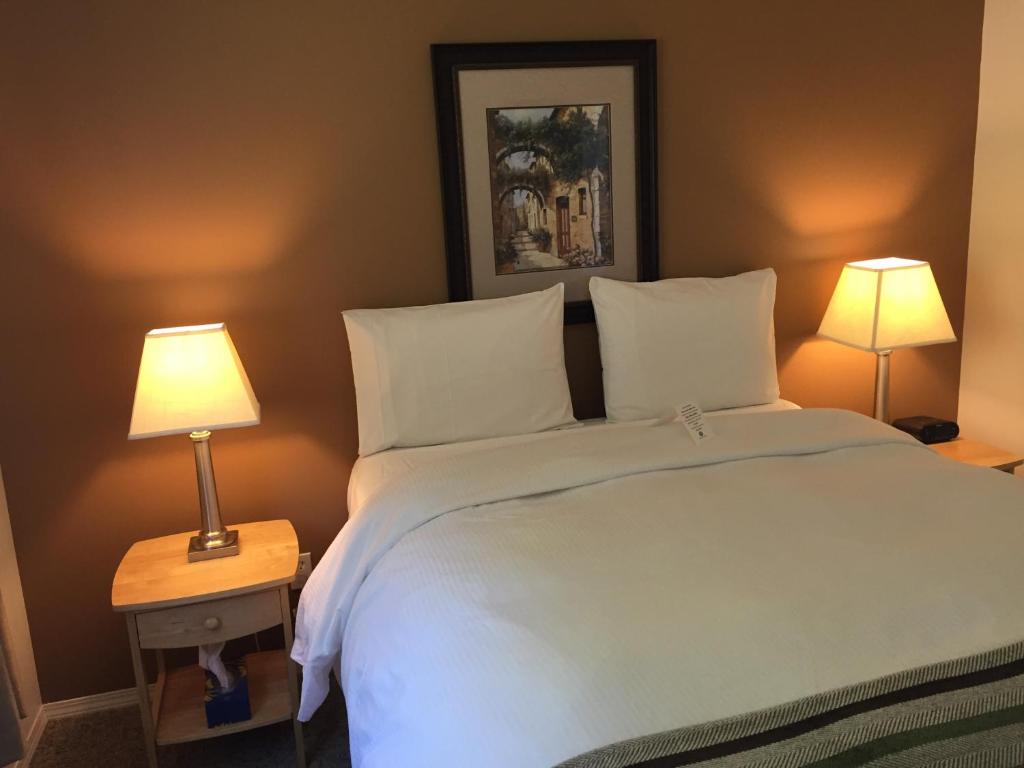 a bedroom with a large white bed with two lamps at Driftwood by the Sea Inn in Campbell River