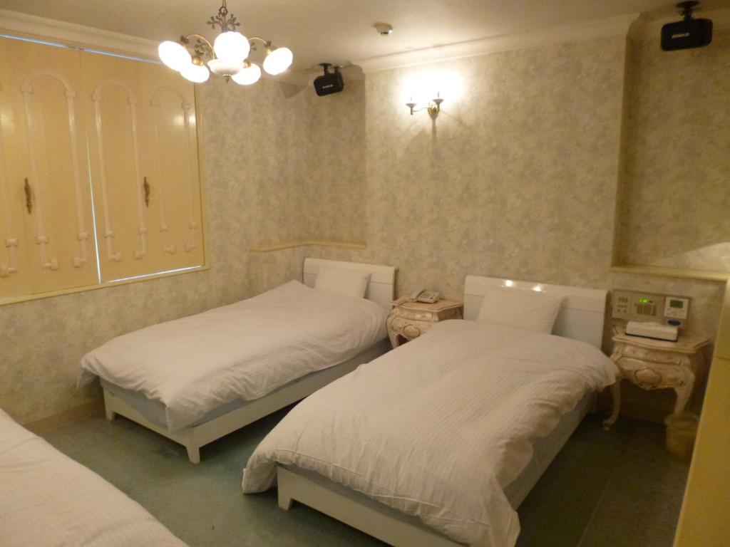 a bedroom with two beds and two night stands at Hotel Sha La La in Okinawa City