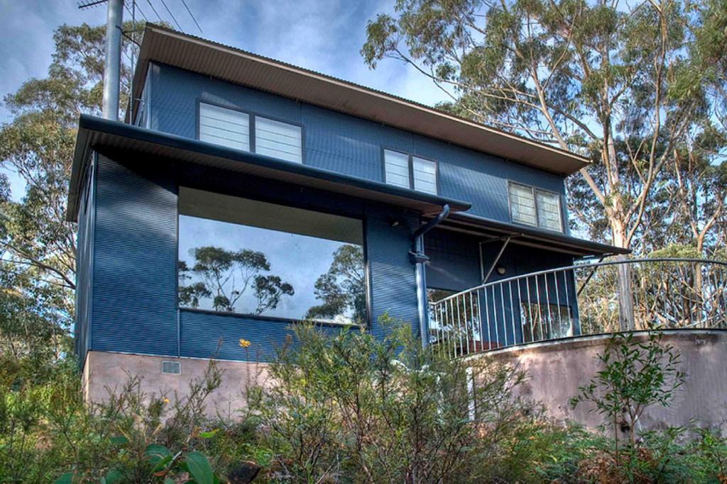 a blue house with a large window and trees at Delmonte in Medlow Bath