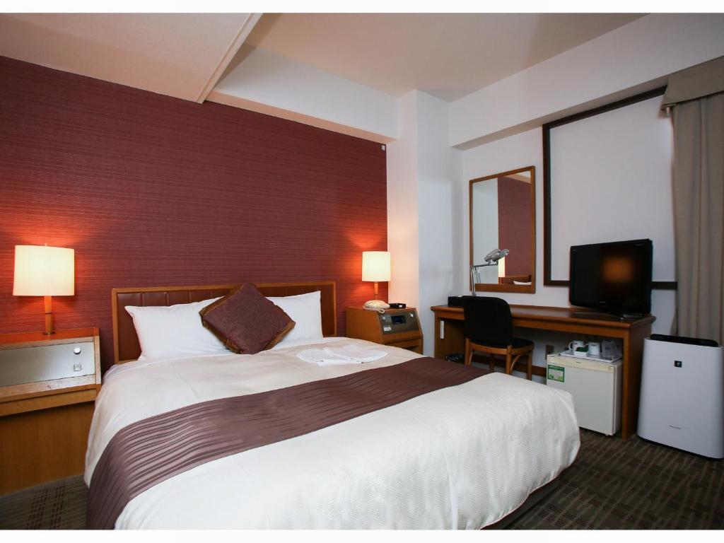 a hotel room with a large bed and a desk at Koriyama Washington Hotel in Koriyama